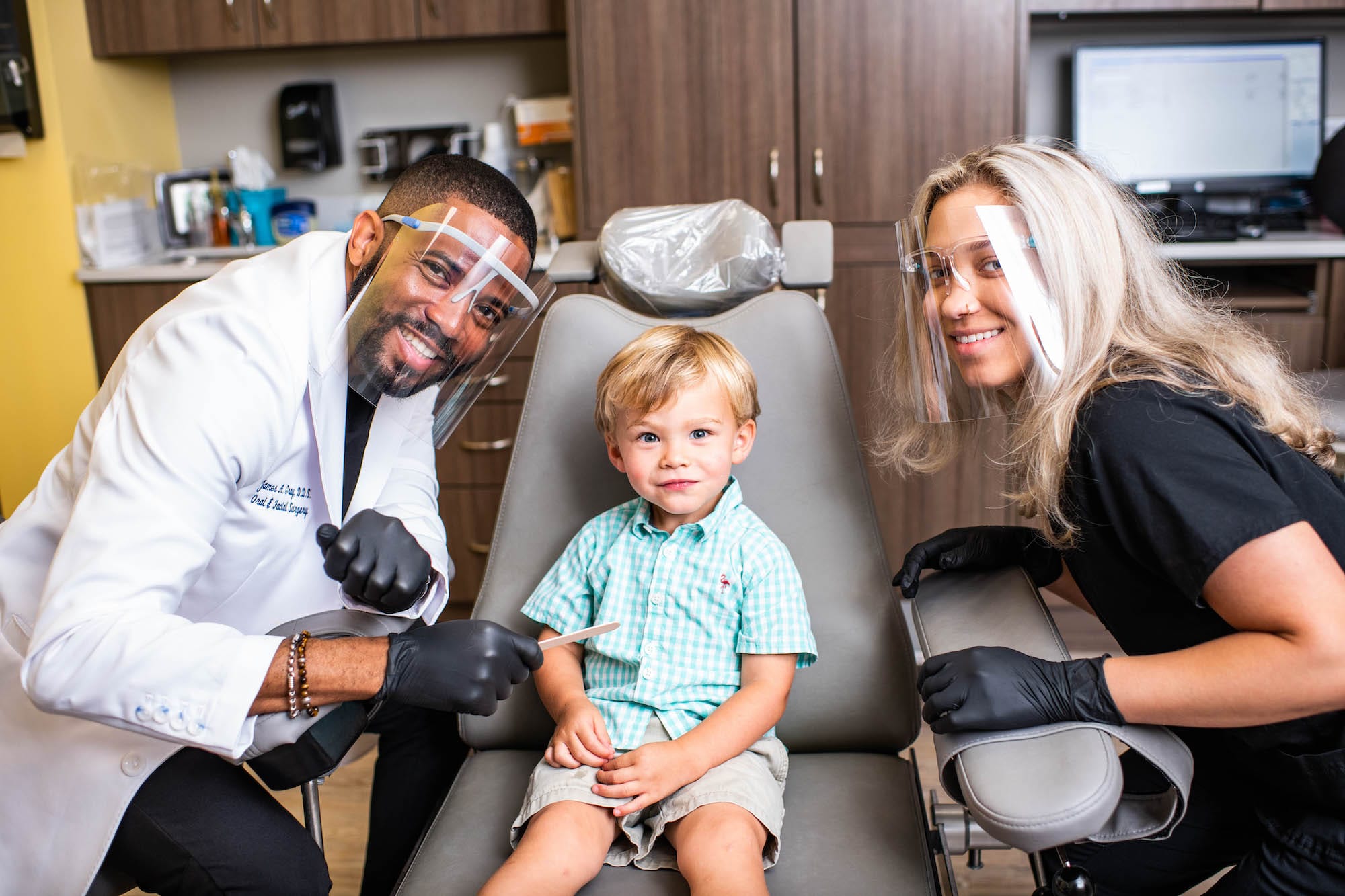 Dentist and Dental Assistant posing with Child in dentist chair